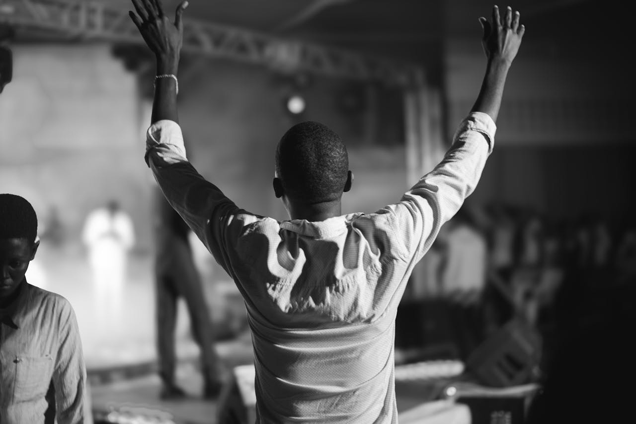 An audience member raises hands in worship during a live concert.